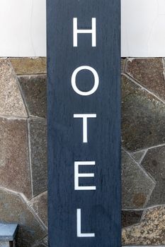 Signpost HOTEL near the facade of the entrance group of the building, Close-up, vertical.