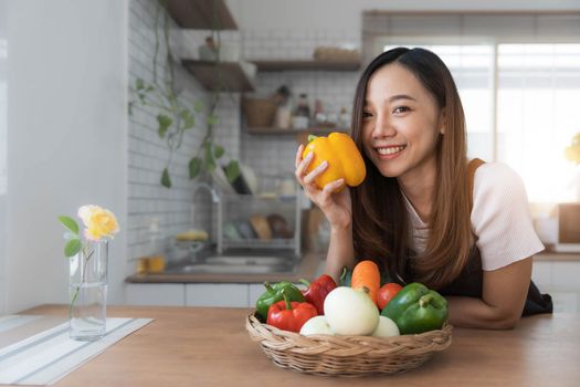 Portrait of young happy woman wearing appron standing in the kitchen room, prepares cooking healthy food from fresh vegetables and fruits...