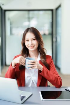Portrait of a business woman talking on the computer and drinking coffee.
