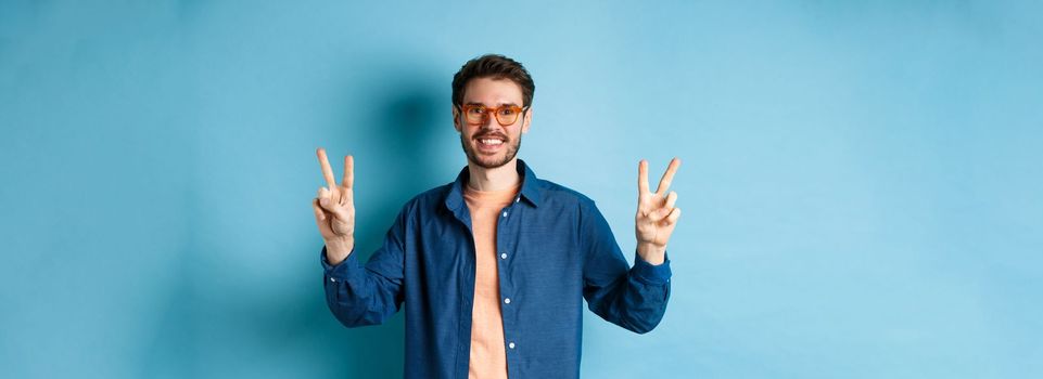 Cheerful guy posing with peace sign in new glasses, concept of eyewear shop promotion.