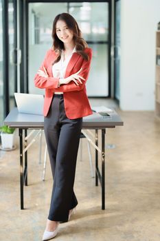 Portrait of a woman business owner showing a happy smiling face as he has successfully invested her business using computers and financial budget documents at work.