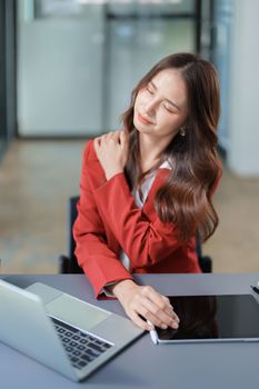 Portrait of young Asian female representative showing shoulder pain from sitting for a long time.