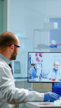 Team of scientist advicing with professional doctor on video call, discussing during virtual meeting in medical laboratory. Chemist examining vaccine evolution using high tech researching treatment