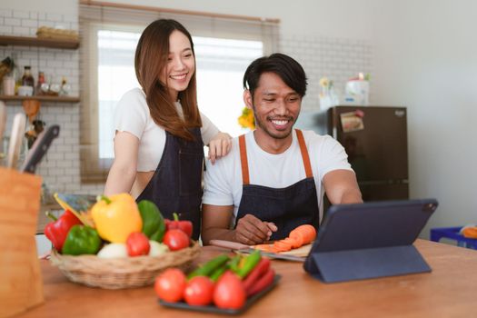 Portrait of young asian couple making salad together at home. cooking food and Lifestyle moment and healthy.