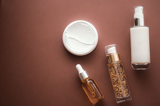 Skincare cosmetics and anti-aging beauty products, luxury skin care bottles, oil, serum and face cream on brown background.