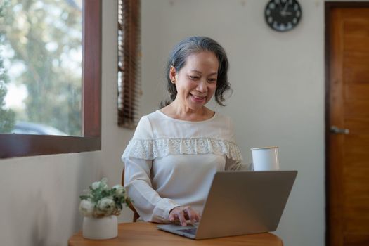 Smart asian mature middle-aged businesswoman CEO boss leader teacher using tablet, e-learning, working remotely online in home office.