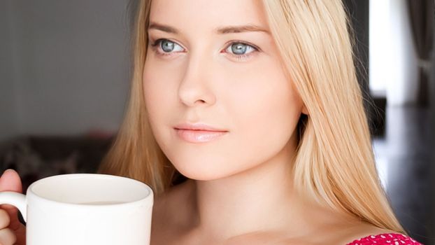 Beautiful blonde woman having a cup of tea in the morning at home.