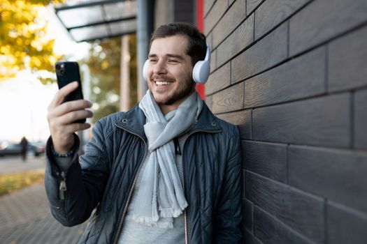 man on the street in headphones listening to music looking at the smartphone screen.