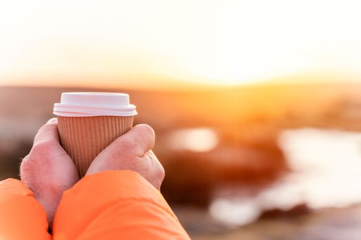 a craft cup in the hands of a traveler at dawn against the background of the rising sun. Travel Lifestyle concept. Local tourism concept.