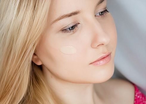 Beautiful blonde woman with liquid make-up foundation on her skin.