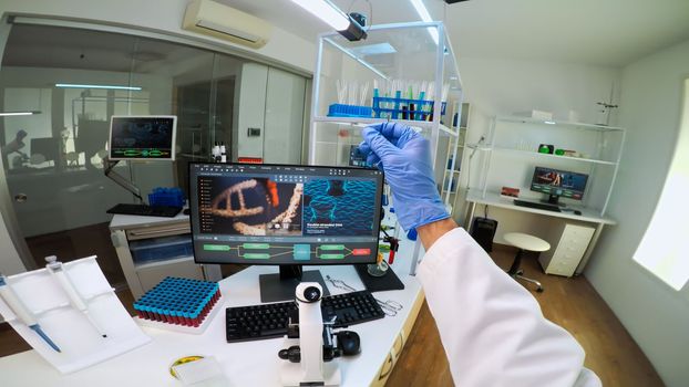 POV of scientist looking at biological samples under microscope typing on pc. Team of chemists working in lab, examining virus evolution using high tech for scientific research of vaccine development.