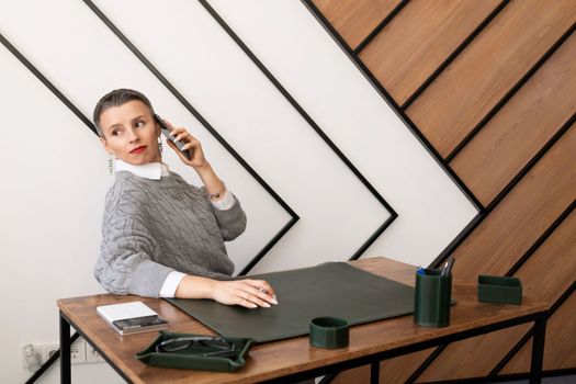 Business woman with short haircut talking on the phone in the office.