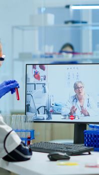 Scientist listening professional doctor on video call, discussing during virtual meeting in medical research laboratory. Chemist examining vaccine evolution using high tech researching treatment