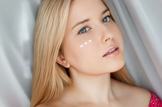 Beautiful woman with skincare cream on her face.