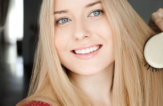 Beautiful happy woman combing her long blond hair.