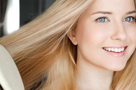 Beautiful happy woman combing her long blond hair.