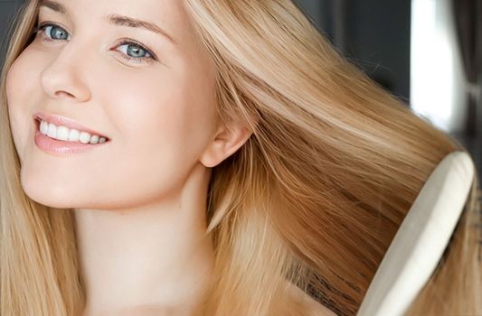 Beautiful happy woman combing her long blond hair.