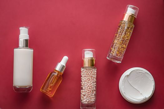 Skincare cosmetics and anti-aging beauty products, luxury skin care bottles, oil, serum and face cream on coral background.