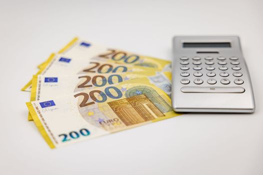 200 Euro banknotes and calculator photographed from the side with shallow depth of field