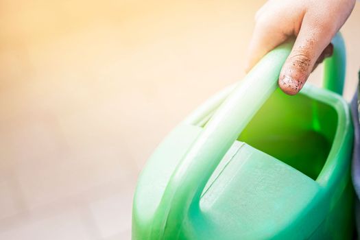 Little hand is holding a watering can. Close up.