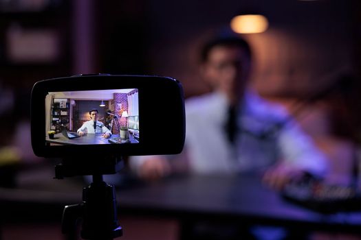 Asian vlogger filming video on camera, creating content for social media channel and broadcasting live discussion. Using audio and sound equipment at production station, recording vlog.