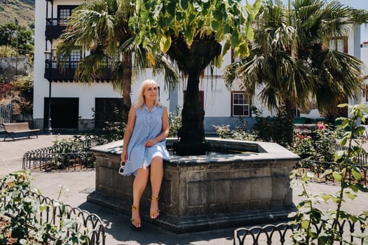 a blonde woman in a sundress sits on the street of the Old town of Icod de los vinos on the island of Tenerife.Spain, Canary Islands