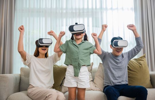 Happy family have mother father and daughter watching movie or playing video game, Asian family wear vr glasses headsets fun sitting on sofa in living room, game entertainment innovation technology