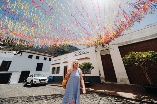 a blonde in a sundress with a backpack walks along the street of the Old town of Garachico on the island of Tenerife.Spain, Canary Islands