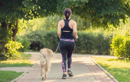Sport girl running with golden retriever dog outdoors. Young woman jogging with doggy pet at summer