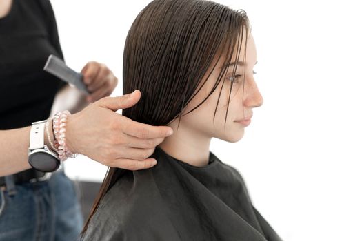 Hairdresser preparing hair of girl for haircut. Female child in beauty salon
