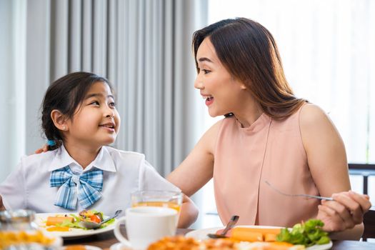 Family breakfast. Mom and little preschooler have fun smile eating meal together, Asian mother and child daughter having breakfast on food table, Healthy food at home in morning before go to school