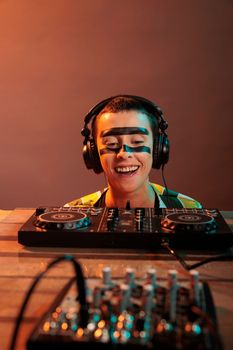 Young performer looking at dj turntables in studio, preparing to mix techno music and have fun at nightclub. Woman with crazy make up watching mixer on table, look closely and acting silly.