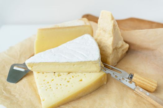 Different types of cheese lie on top of each other with cheese knives. A delicious delicacy