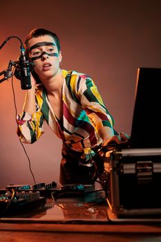 Woman performer producing techno music at mixer, having crazy make up and playing with audio stereo equipment. Artist mixing sounds at turntables to make musical performance in studio.
