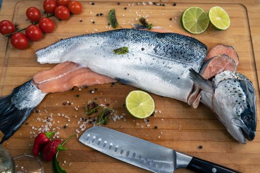 Fresh raw salmon fish on the kitchen wooden board with spices and lime