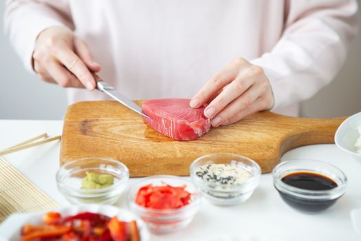 The process of preparing sushi, preparing all the ingredients for sushi, the girl cuts the tuna