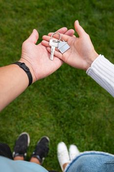 Keys with a keychain in the form of a metal house from a new house or apartment in the hands of a young family. Happiness from buying a home. Vertical photo