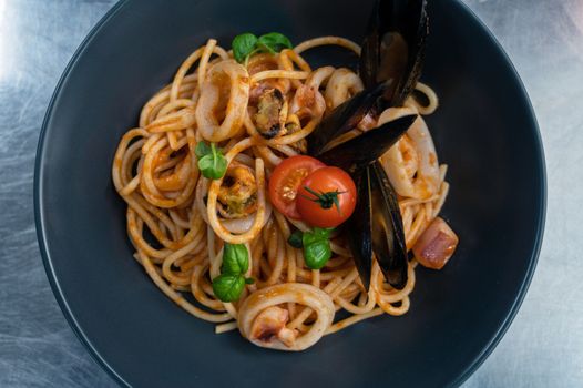 Seafood Pasta with mussels with basil and tomato in black plate