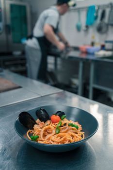 Chef preparing Seafood Pasta with mussels with basil and tomato in black plate