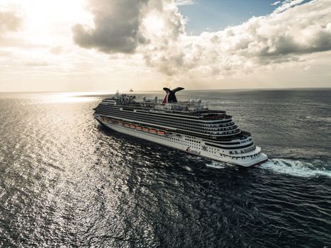 Cruise ship sailing through the caribbean ocean taking all the summer tourists on holiday on the island drone footage aerial view. High Quality Photo 