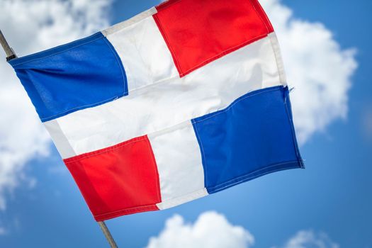 Dominican Republic National Flag Waving on pole against sunny blue sky in Punta Cana
