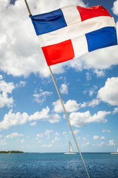Dominican Republic National Flag Waving on pole against sunny blue sky in Punta Cana