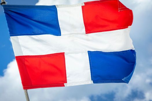Dominican Republic National Flag Waving on pole against sunny blue sky in Punta Cana