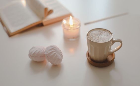 coffee cup, cotton flower, open book on a white table background top view. minimal home interior decor. 