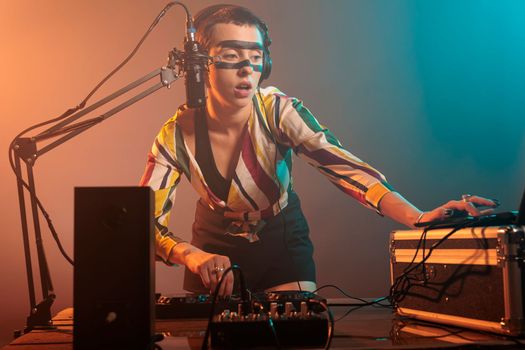 Disc jockey mixing techno music with turntables, musical performer playing sounds to produce melody at mixer. Performing song with electronics equipment and audio instrument, vinyl remix.