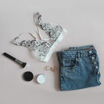 Top view of female casual outfit. Flat lay composition with women underwear, bra, jeans, cosmetics 