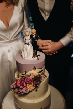 Three-level wedding cake with figures of people on it.