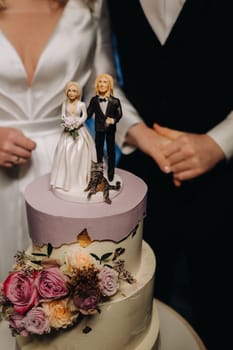 Three-level wedding cake with figures of people on it.