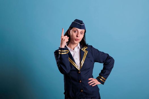 Flight attendant pointing up with index finger, aviation academy stewardess advertising product. Confident air hostess showing upwards with forefinger, airlines promotion
