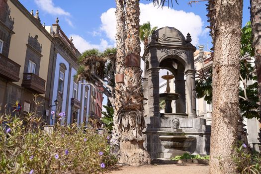 Outdoor fountain with medieval architecture and palm trees at Plaza del Espiritu Santo in Vegueta, Las Palmas de Gran Canaria, Spain